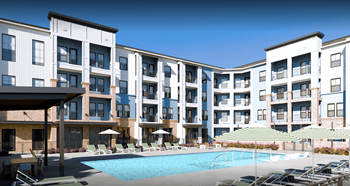 a swimming pool with chairs and umbrellas in front of an apartment building at Livano Prosper, Prosper Texas